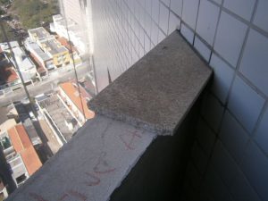 Foto nº 02 – Vista da soltura e queda de uma peça em granito no peitoril do terraço de um determinado apartamento, devido à péssima colagem executada. 