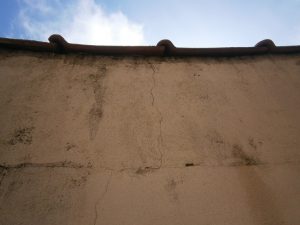 Vista das fissuras sobre o muro de divisa, devido à ausência de rufo metálico para a quebra do fluxo d’água pluvial.